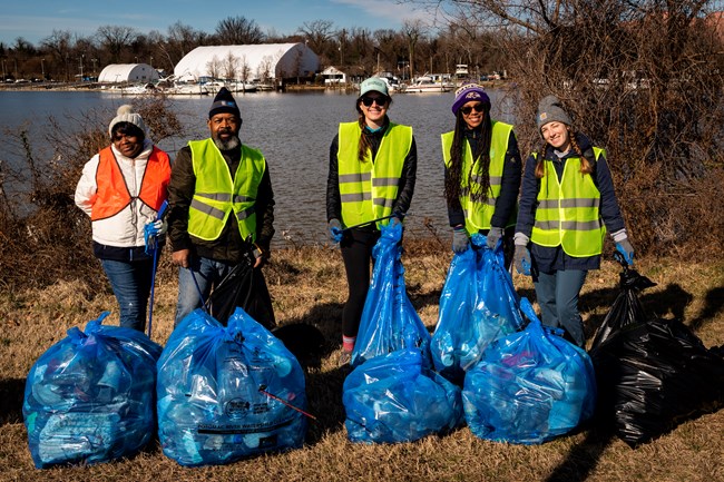 Volunteers holding trash bags by the Anacostia River.